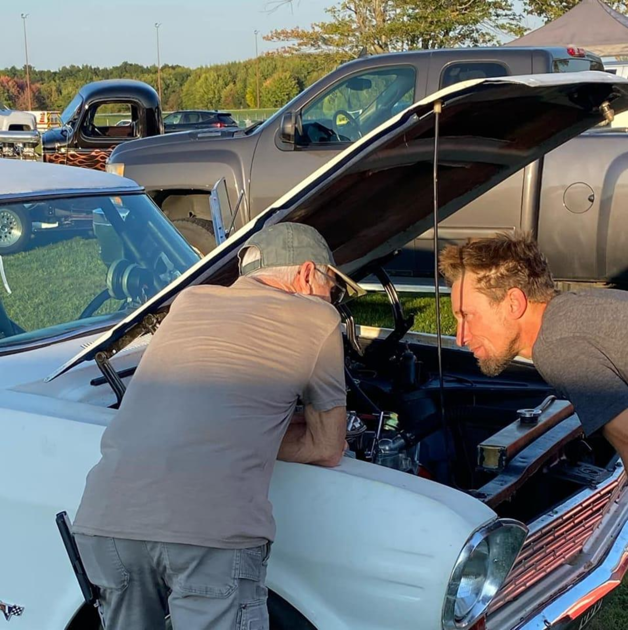 Two people leaning over the Nova engine bay during inspection and tuning